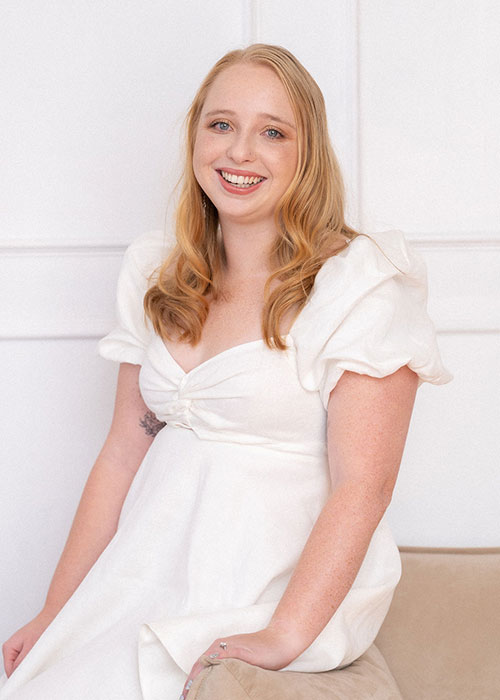 A woman posing for a photo in a white dress at Matchsticks Marketing Agency