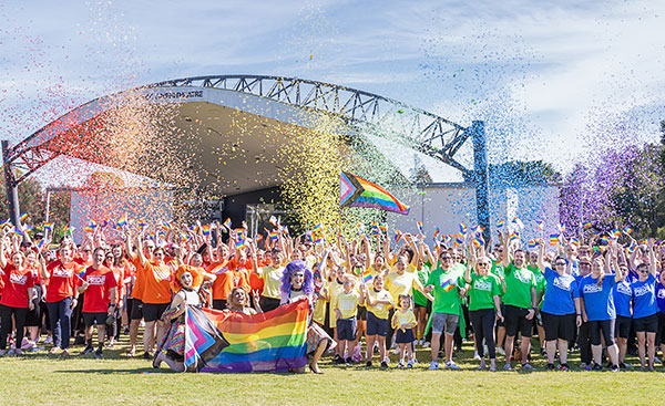 A large group of people celebrating at the Moreton Bay Pride Festival with confetti.