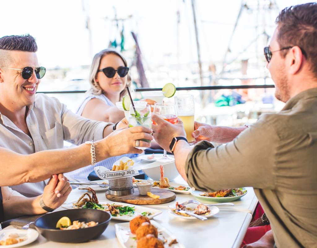 A group of people toasting at an outdoor table during a marketing photoshoot.