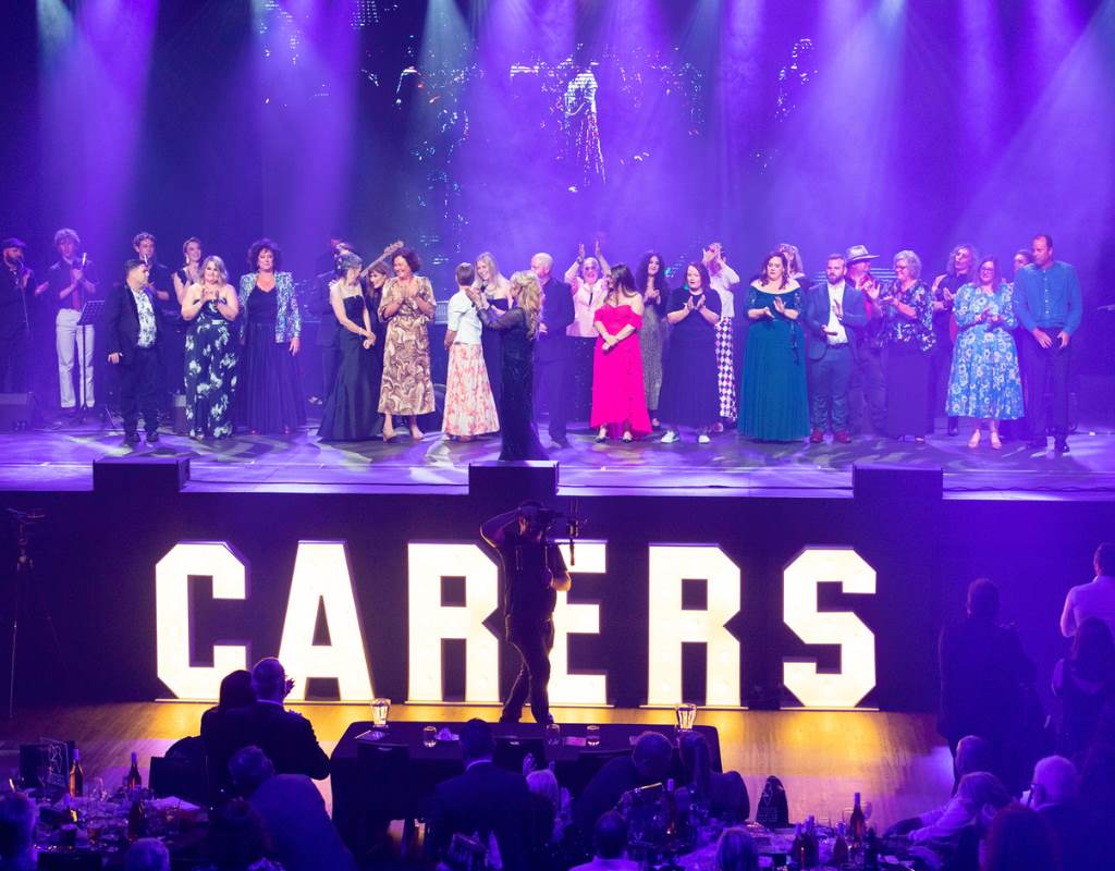 A group of Unsung Heroes standing on stage for the Carers Foundation